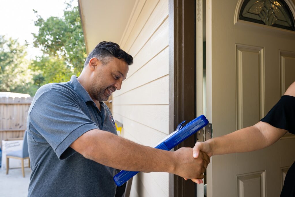 Houston homeowner greeting a licensed plumber at the front door while choosing the right plumber