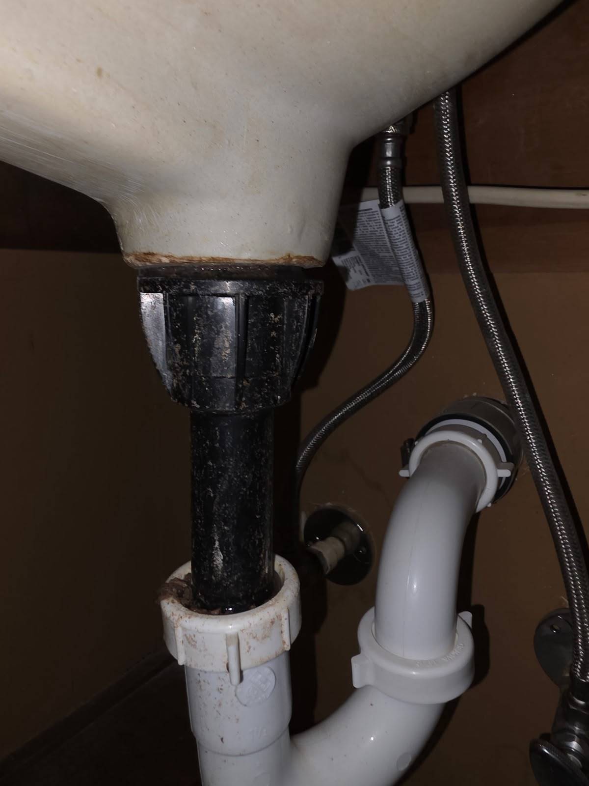 Corroded sink tailpiece and trap connection before repair under a Katy TX bathroom sink