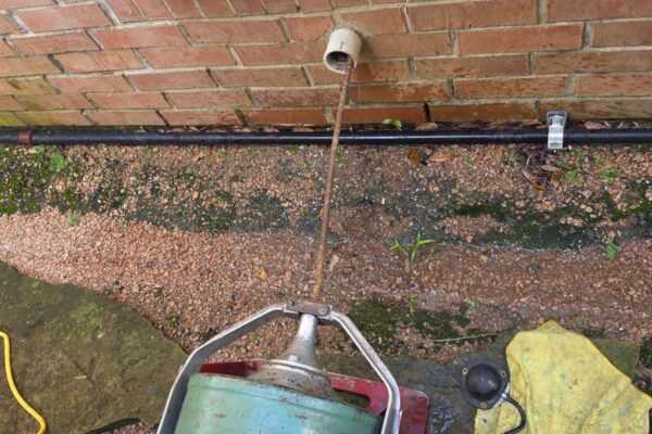 Drain machine cable clearing a sewer line through the exterior cleanout at a River Oaks Houston home